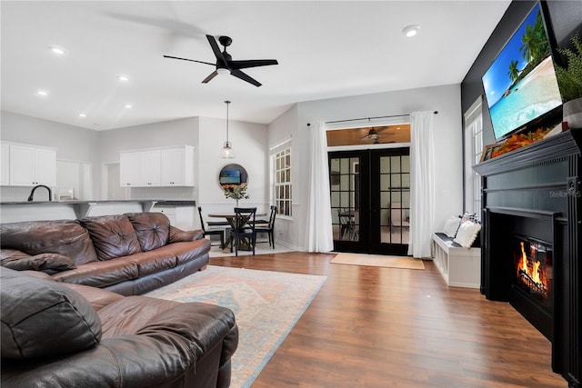 living room featuring sink, light hardwood / wood-style flooring, french doors, and ceiling fan