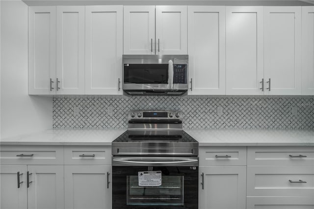 kitchen featuring white cabinetry, backsplash, appliances with stainless steel finishes, and light stone countertops