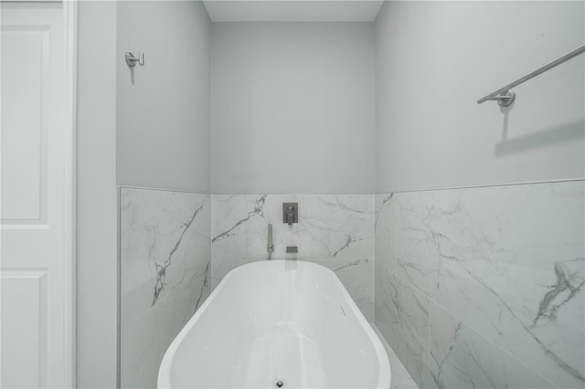 bathroom featuring tile walls and a tub to relax in