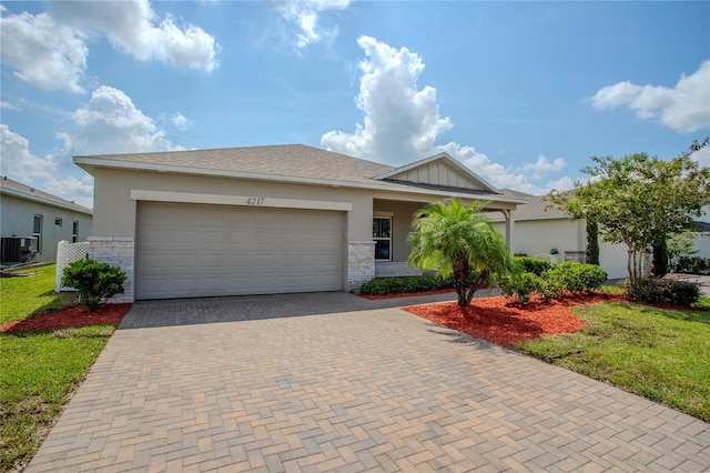 view of front facade with a garage, a front lawn, and central AC