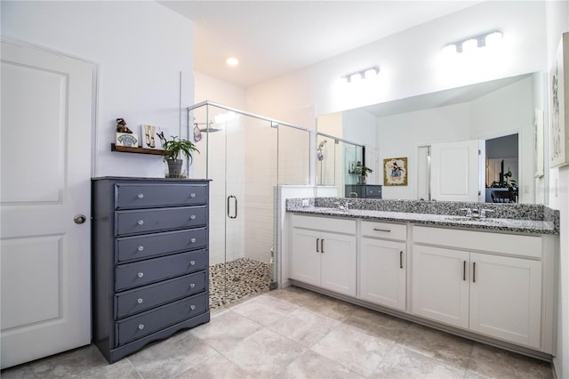 bathroom featuring a shower stall, double vanity, a sink, and tile patterned flooring