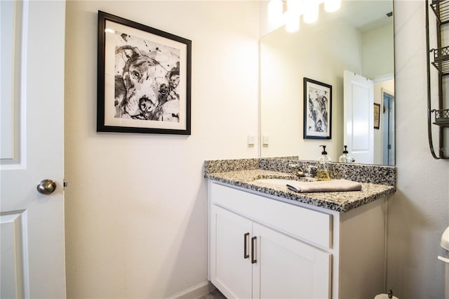 bathroom with toilet, vanity, and baseboards