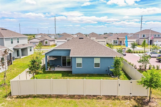 back of house with a fenced backyard, a shingled roof, a residential view, and stucco siding