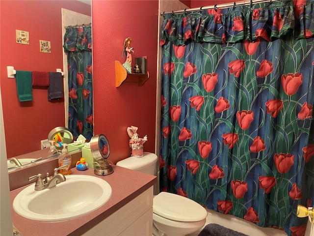 bathroom with curtained shower, vanity, and toilet