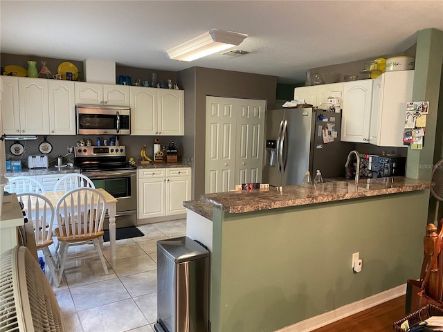 kitchen featuring kitchen peninsula, white cabinetry, light tile patterned floors, and stainless steel appliances