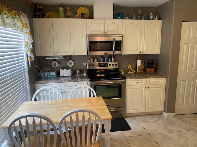 kitchen with appliances with stainless steel finishes, white cabinetry, and light tile patterned floors