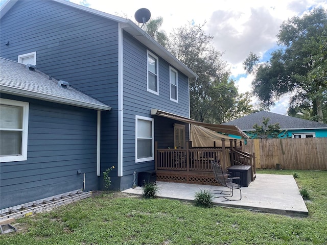 back of house featuring a patio, a wooden deck, and a lawn