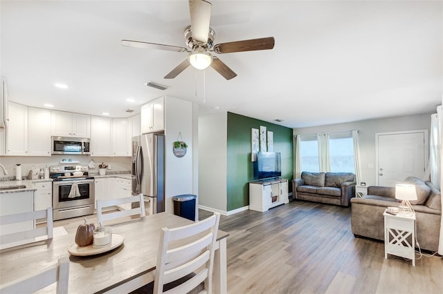 kitchen featuring light hardwood / wood-style floors, white cabinetry, stainless steel appliances, ceiling fan, and sink