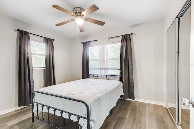 bedroom with ceiling fan, a closet, hardwood / wood-style floors, and multiple windows