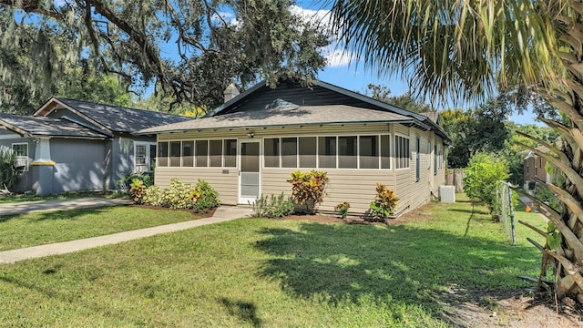 view of front of property featuring a front lawn, cooling unit, and a sunroom