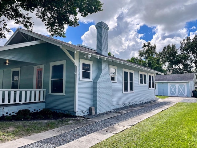 view of property exterior featuring a lawn, a storage unit, and covered porch