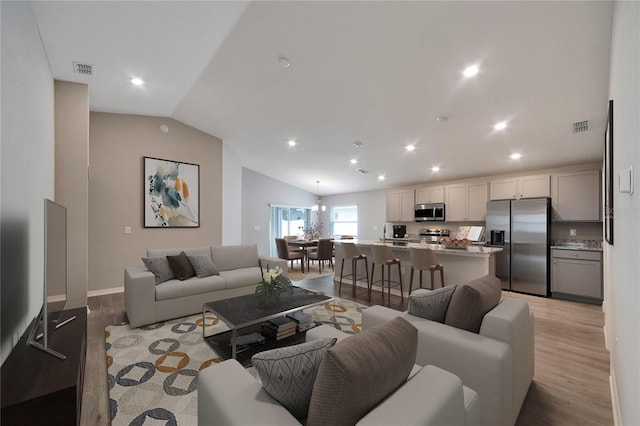 living room with light hardwood / wood-style floors and vaulted ceiling