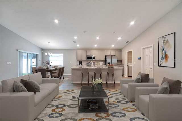 living room featuring lofted ceiling, light hardwood / wood-style flooring, and a chandelier