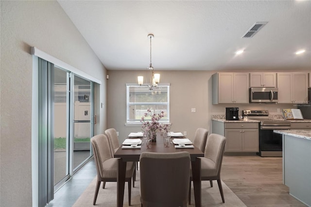 dining area featuring an inviting chandelier, light wood-type flooring, and vaulted ceiling