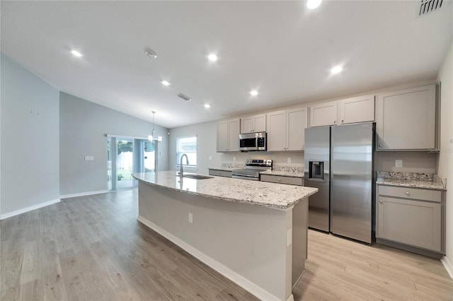 kitchen with a center island with sink, vaulted ceiling, light hardwood / wood-style flooring, and stainless steel appliances