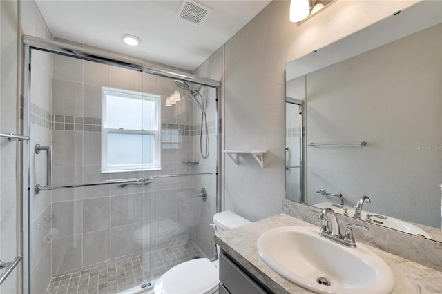 bathroom with vanity, a shower with shower door, and toilet