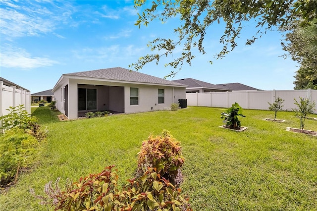 rear view of property with a lawn and cooling unit