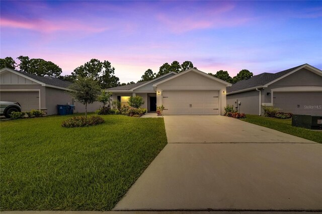 ranch-style home featuring a garage and a yard