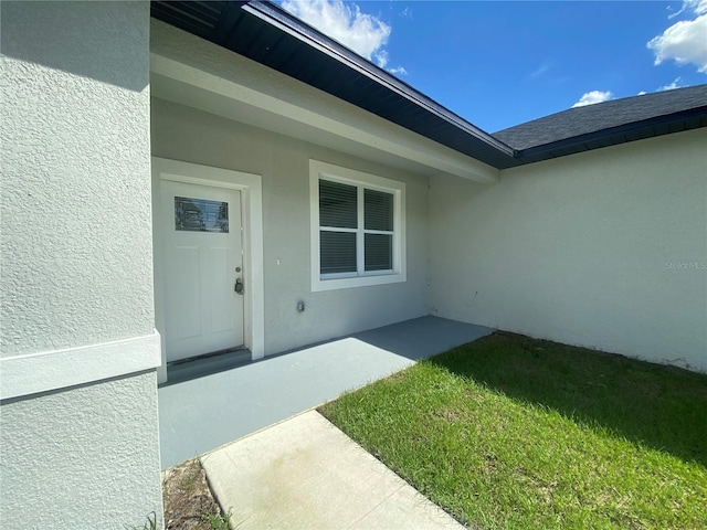 view of exterior entry featuring a yard