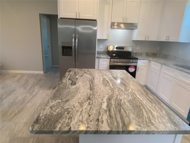 kitchen with light stone countertops, stainless steel appliances, white cabinets, and a kitchen island