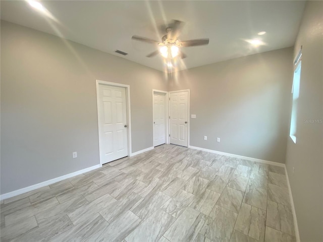 unfurnished bedroom with two closets and ceiling fan