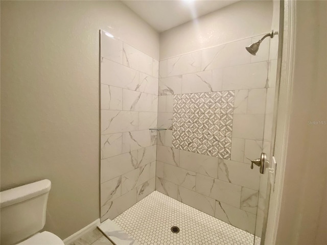 bathroom featuring tiled shower and toilet