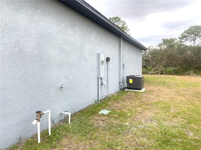 view of side of home featuring a yard and central AC unit