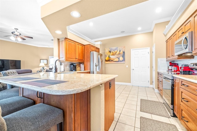 kitchen featuring ornamental molding, kitchen peninsula, tasteful backsplash, stainless steel appliances, and a breakfast bar