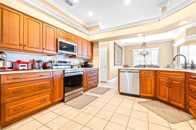 kitchen with appliances with stainless steel finishes, ornamental molding, an inviting chandelier, and pendant lighting