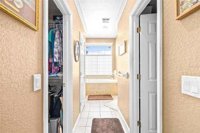 corridor featuring a textured ceiling, crown molding, and light tile patterned flooring