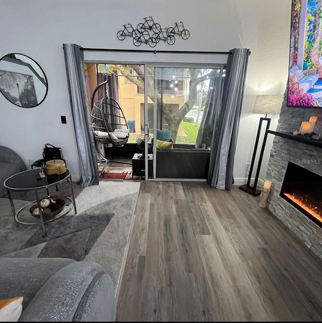 living room with a stone fireplace, hardwood / wood-style floors, and a healthy amount of sunlight