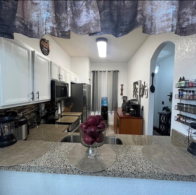 kitchen featuring white cabinets, stainless steel appliances, and light stone counters