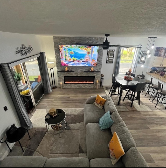 living room with a textured ceiling, hardwood / wood-style flooring, and a large fireplace