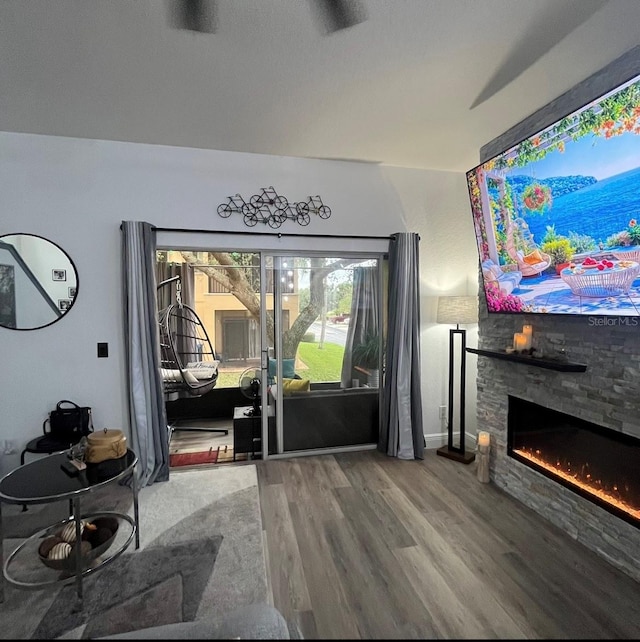 living room featuring a stone fireplace and hardwood / wood-style floors