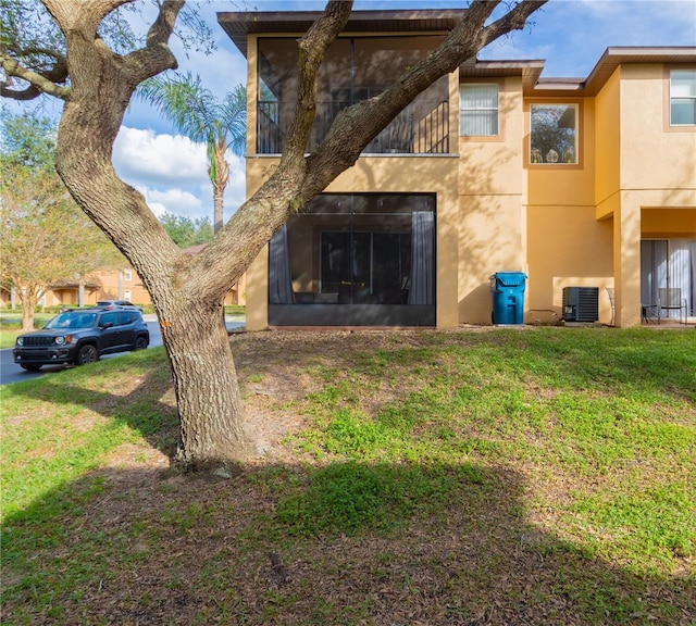 rear view of property featuring a lawn and cooling unit