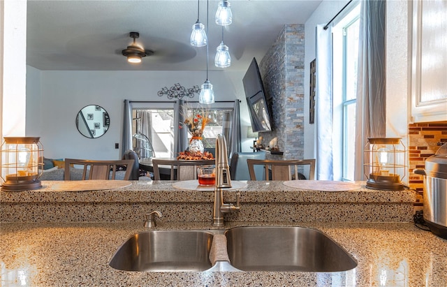 kitchen with backsplash, pendant lighting, sink, and ceiling fan