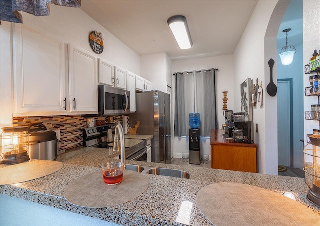 kitchen with stainless steel appliances, light stone counters, backsplash, hanging light fixtures, and white cabinets