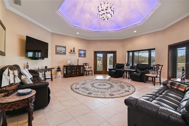 tiled living room featuring ornamental molding, french doors, a tray ceiling, and an inviting chandelier