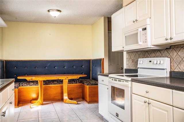 kitchen with white cabinets, a textured ceiling, and white appliances