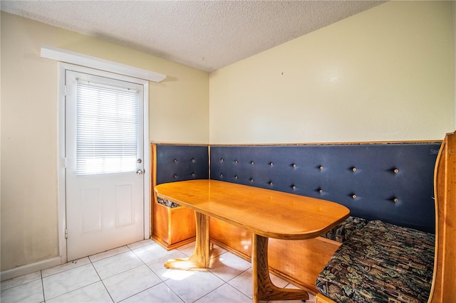 unfurnished dining area featuring a textured ceiling and light tile patterned floors