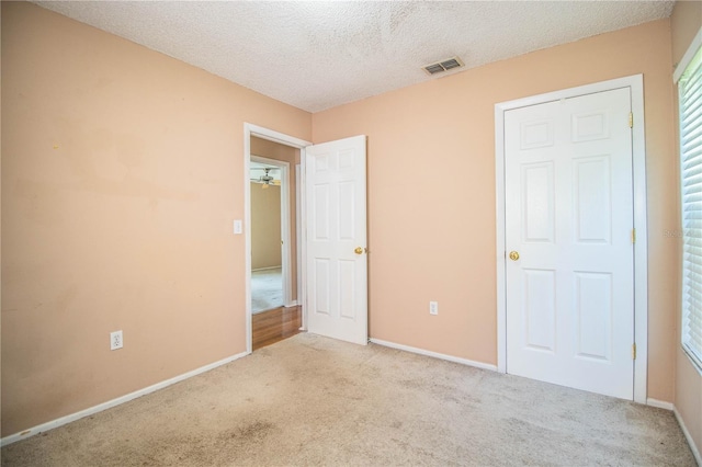 unfurnished bedroom with a textured ceiling and light colored carpet