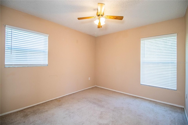 carpeted spare room featuring a textured ceiling, a healthy amount of sunlight, and ceiling fan