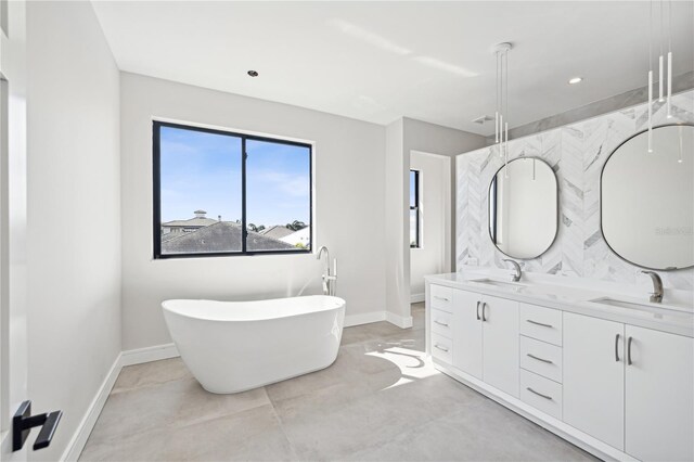 full bath with baseboards, a soaking tub, and a sink