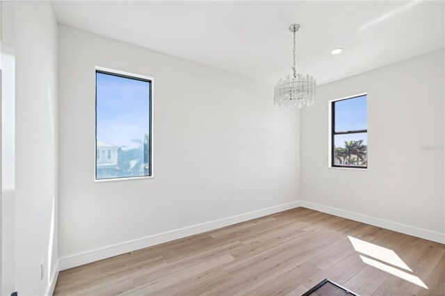 unfurnished room featuring light wood-style floors, recessed lighting, a chandelier, and baseboards
