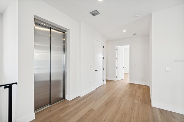 hallway featuring recessed lighting, elevator, light wood-style flooring, baseboards, and visible vents