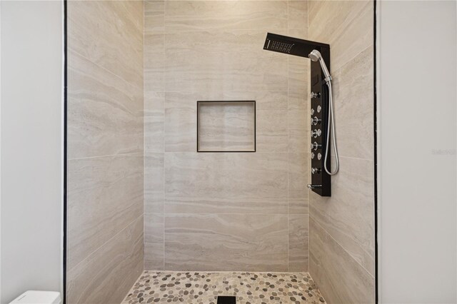 full bath with toilet and a tile shower
