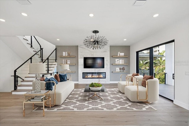 living room with a large fireplace, a notable chandelier, and light wood-type flooring