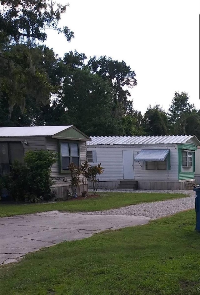 manufactured / mobile home with entry steps, a front lawn, and metal roof