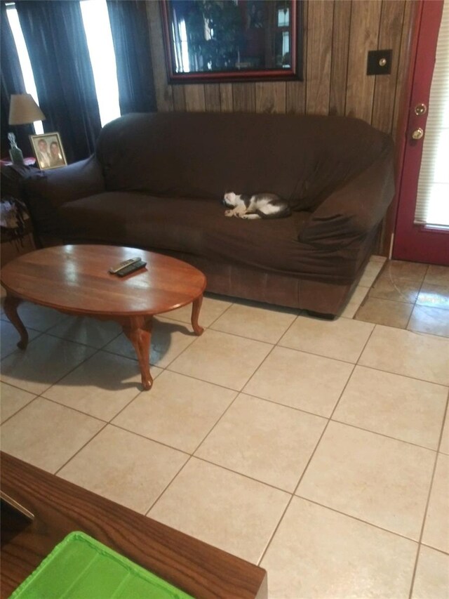 living room featuring wood walls and light tile patterned floors