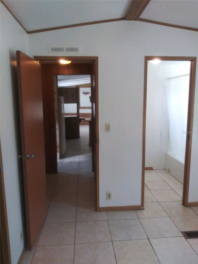 hallway with light tile patterned flooring, vaulted ceiling, visible vents, and crown molding
